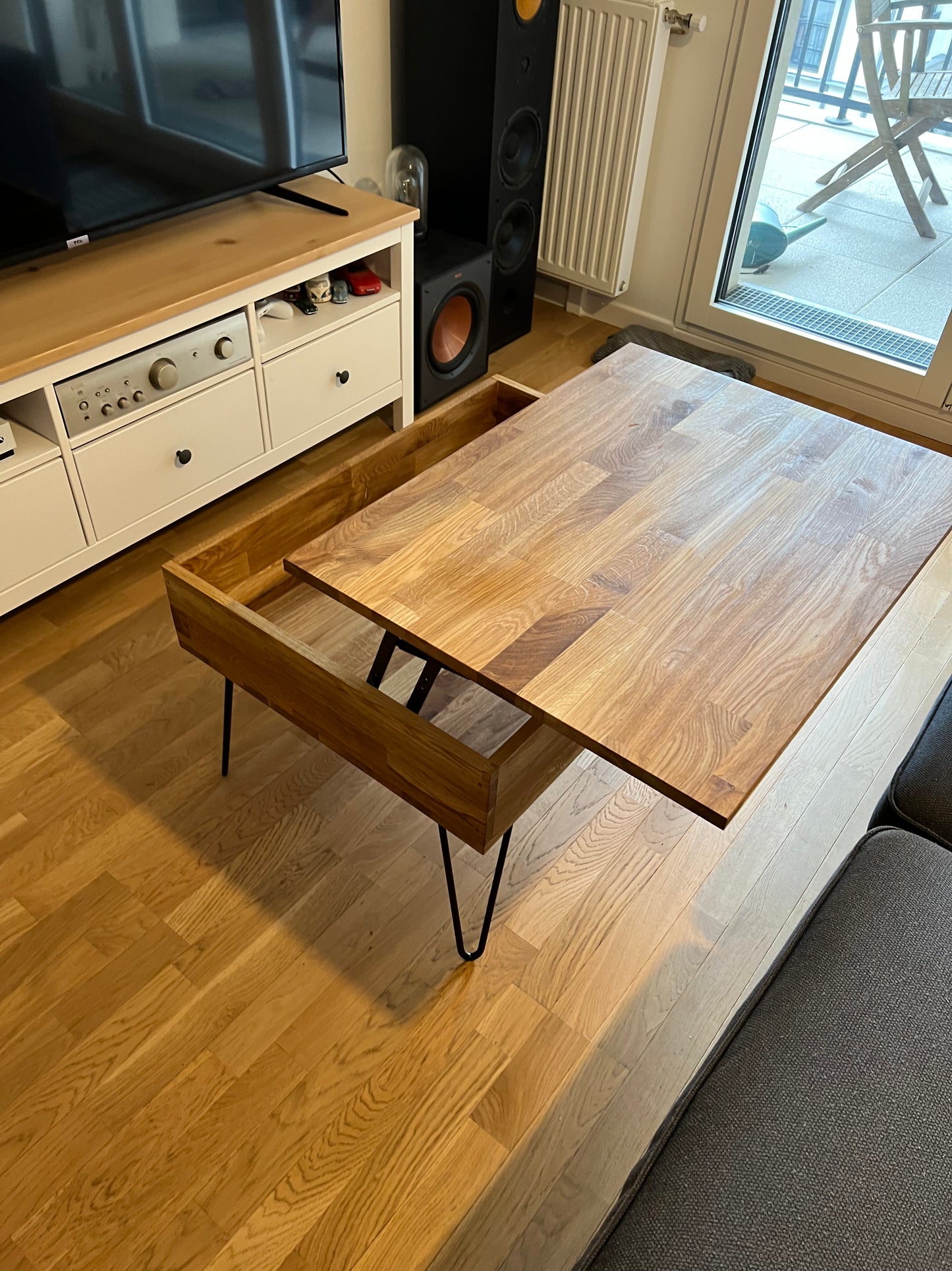Table basse relevable en position relevé en bois. Pieds acier épingle